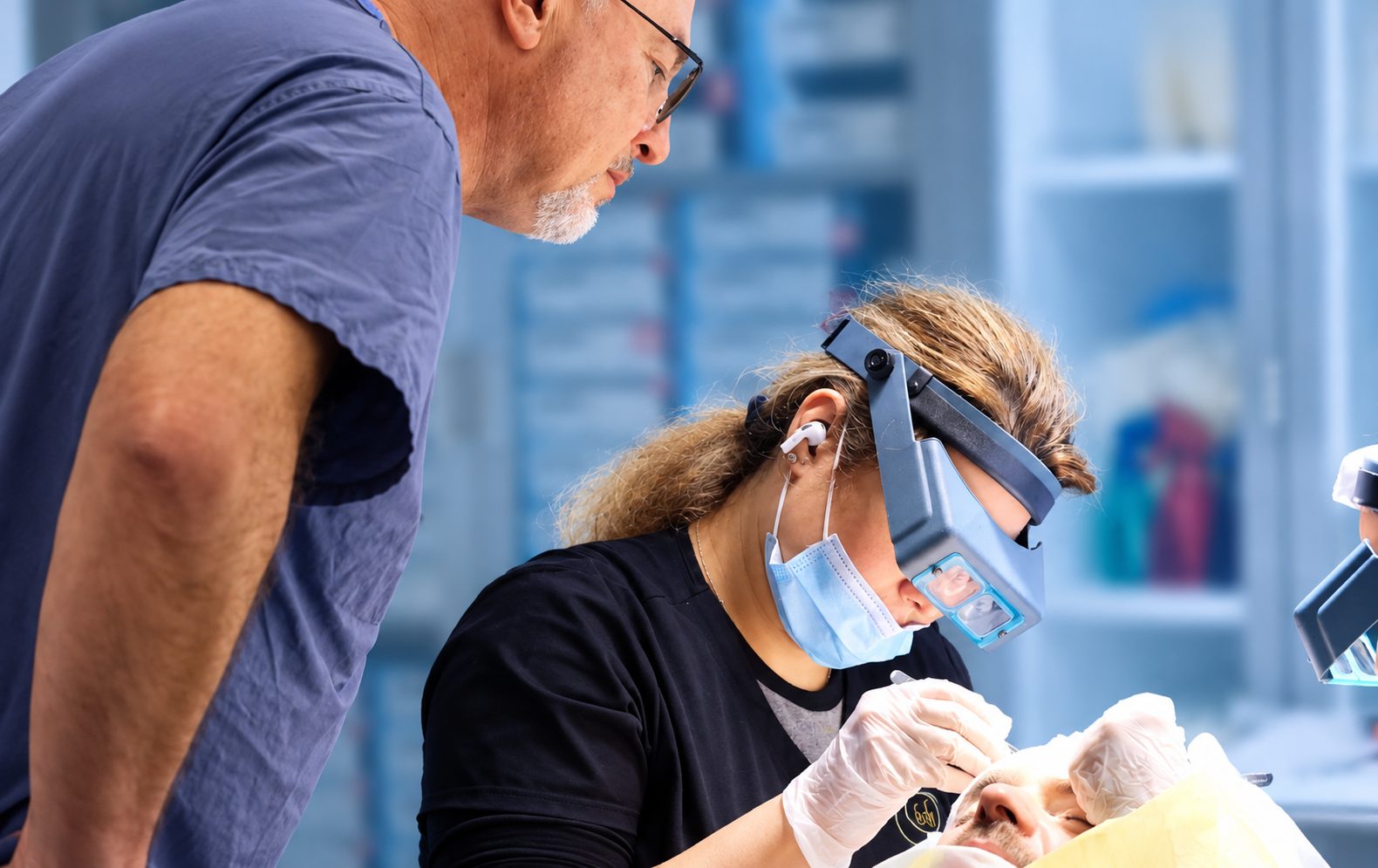 Dr. Val Prokurat, MD watching a technician place grafts under magnifying loupes during an FUE procedure at Nova Medical Long Island